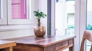 A wooden table with a potted plant, a chair, and a window with blinds.