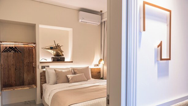 A bedroom with a bed, wooden wardrobe, and a ship decoration on the wall.