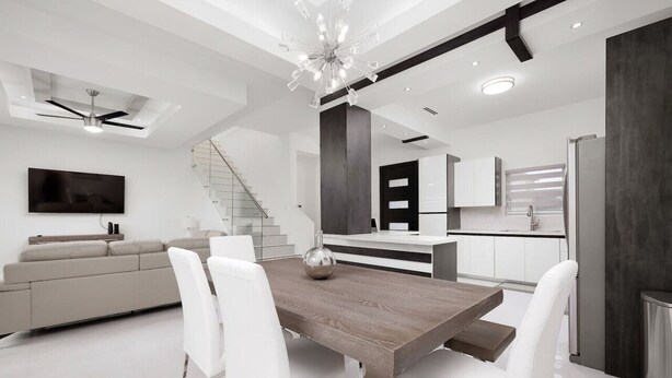 Eine moderne Küche mit einem Holzesstisch und weißen Stühlen, einem eingebauten Backofen und einem Edelstahl-Kühlschrank.