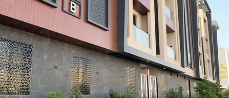 A modern building with a mix of red and beige exterior walls, large windows, and a flat roof.