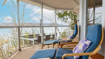 A sunroom with large windows, blue cushioned chairs, and a view of the landscape.