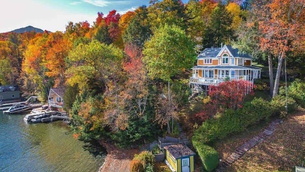 A house surrounded by autumn foliage, a dock, and a small boat.