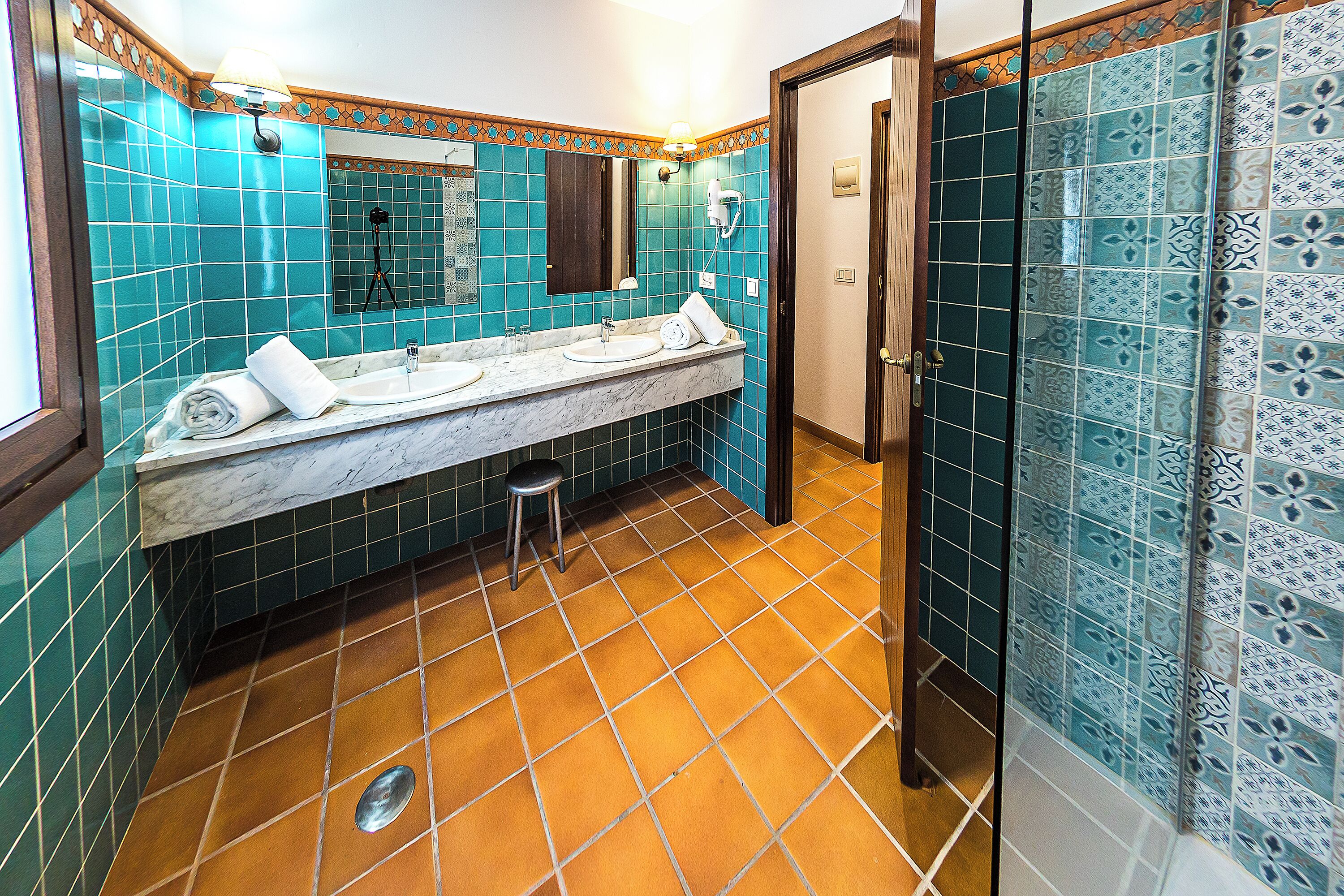 A bathroom with a marble sink, a mirror, and a shower area.