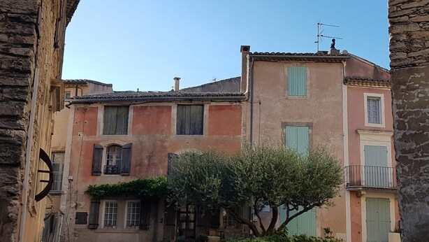 A traditional building with a stone facade, multiple windows with shutters, and a small tree in front. - Luberon - Vue Exceptionnelle - Location de Maisonnette 4 Personnes (Ménerbes)