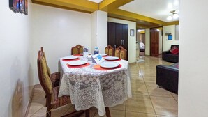 Un comedor con una mesa preparada para cuatro personas, un sofá y un armario al fondo.