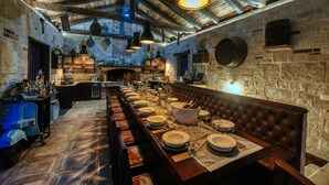 A long dining table set with plates, glasses, and a centerpiece, in a rustic room with exposed wooden beams and stone walls. - Villa Marta Zadarvillas (Nin)