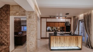 A modern kitchen with a stone accent wall, a wooden island, and a view of the living area. - Villa Marta Zadarvillas (Nin)