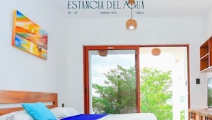 A bedroom with a bed, a blue blanket, a painting, and a ceiling fan.