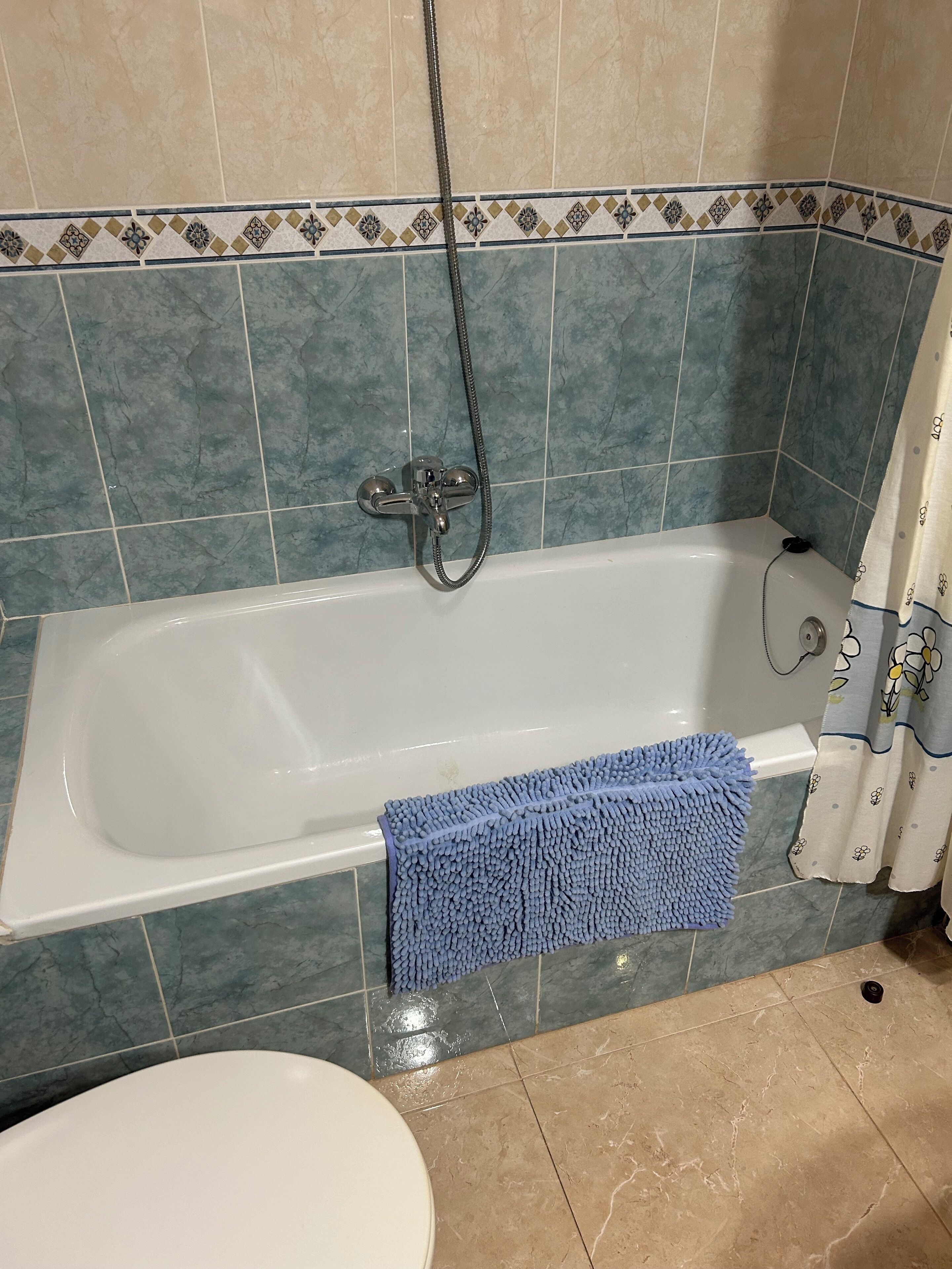 Een badkamer met een bad, douche en toilet.
