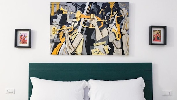 Un dormitorio con una cama, un cabecero verde y un cuadro abstracto grande en la pared.