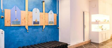Um quarto com parede azul, um banco de madeira e uma porta branca.
