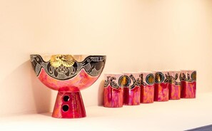 Un cuenco decorativo con diseño de pájaro y varios recipientes cilíndricos con patrones similares.