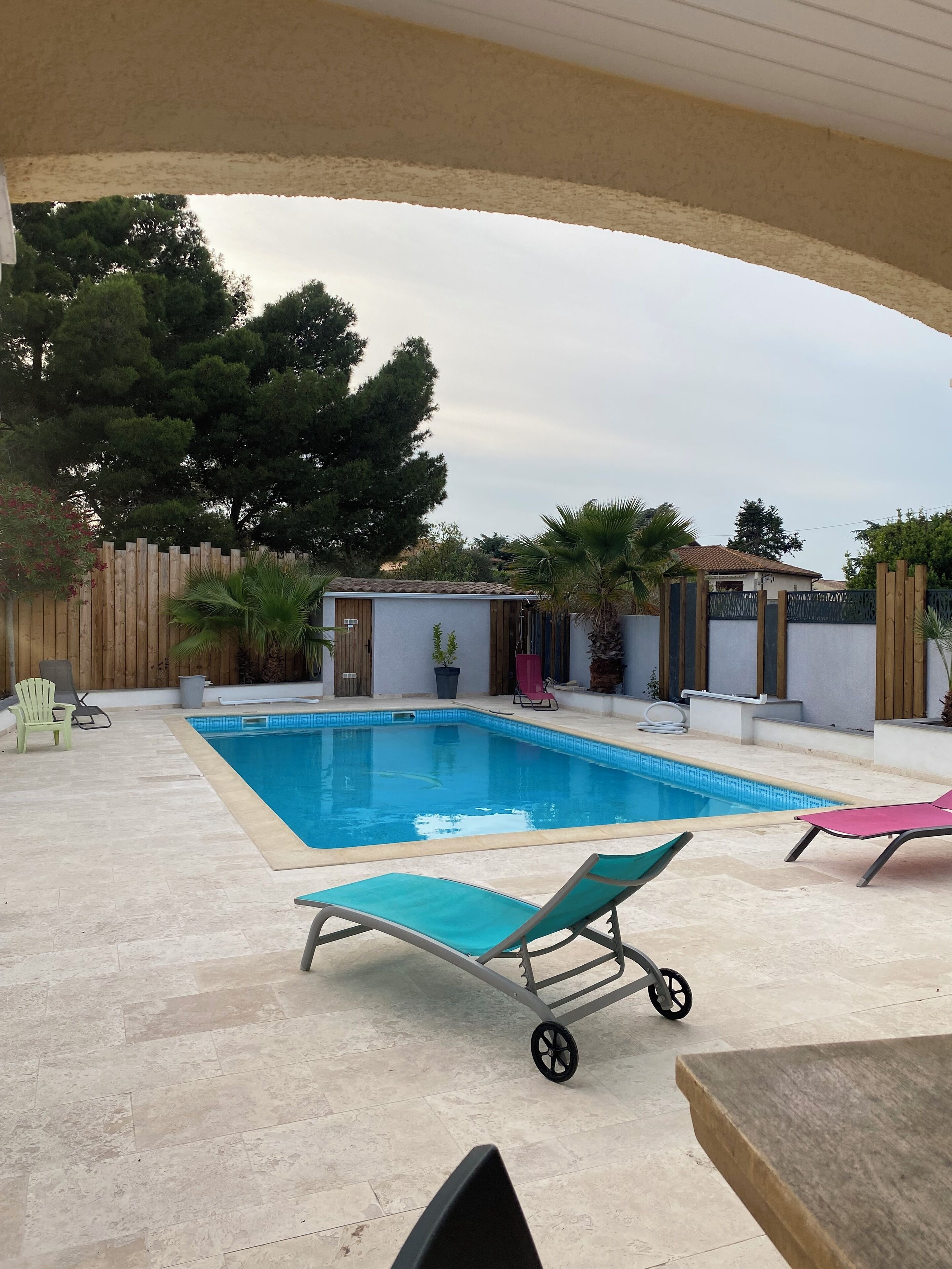 Una piscina amb gandules, un edifici petit i una tanca de fusta.
