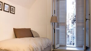 A bedroom with a bed, a floor lamp, and a window with blinds. - Manuela Apartments 1 Plebiscito Quartieri Spagnoli (Naples)