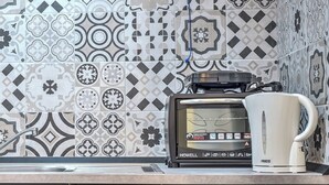 A kitchen with a coffee maker and toaster on the counter, and patterned tiles on the wall. - Manuela Apartments 1 Plebiscito Quartieri Spagnoli (Naples)
