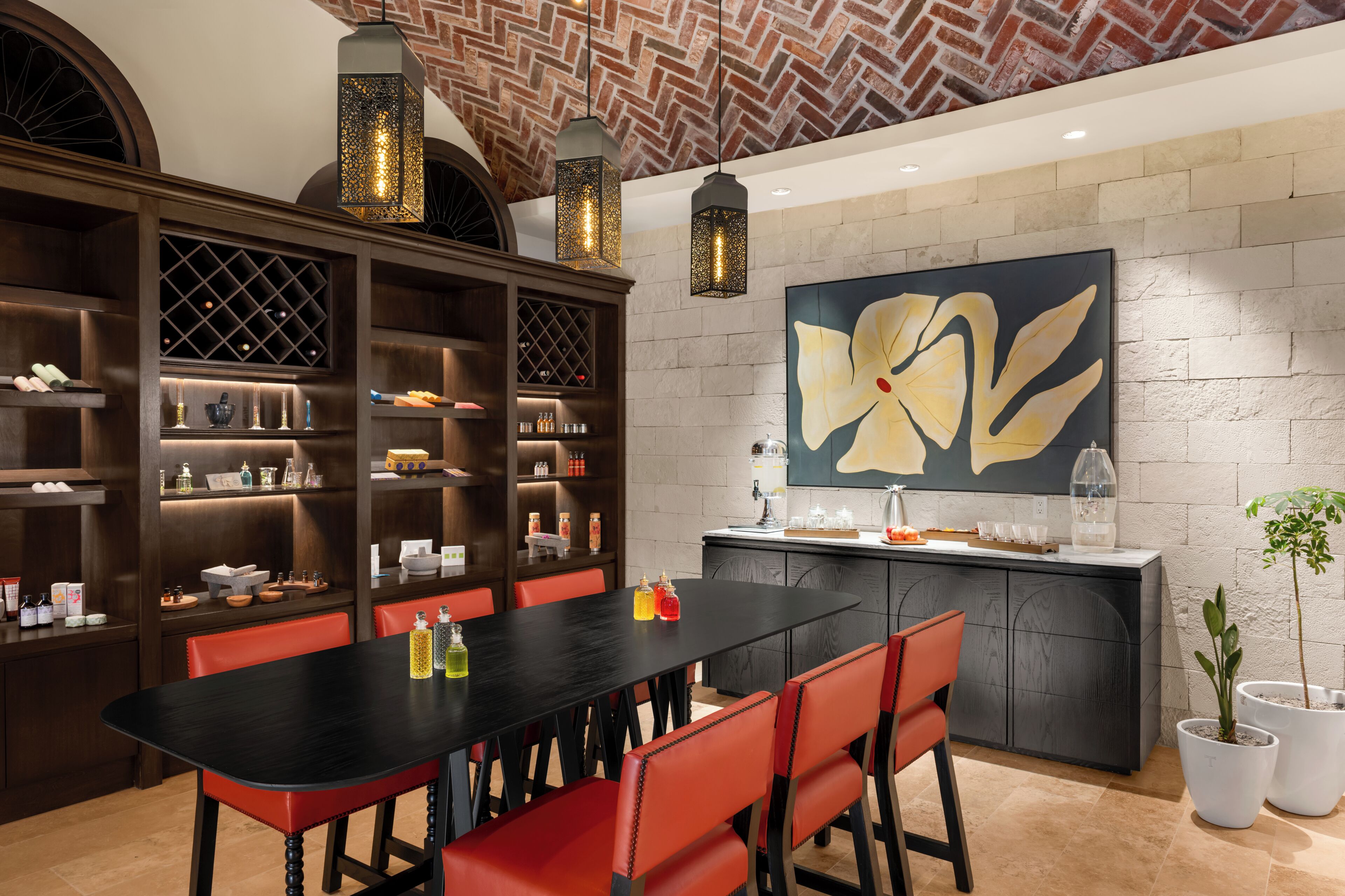 A modern kitchen with a black countertop, red chairs, and a large flower painting on the wall.