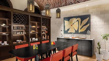 A modern kitchen with a black countertop, red chairs, and a large flower painting on the wall.