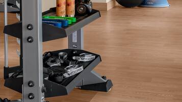 A gym with a weightlifting rack, kettlebells, exercise balls, and resistance bands.