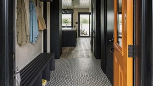Un couloir doté d’un sol à motifs, d’un banc et d’une porte donnant sur une pièce avec vue sur l’extérieur.
