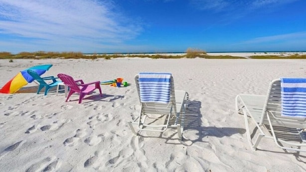 A beach with two sun loungers, a colorful kite, and a beach ball. - One Bed/ One Bath Condo- Step From Siesta Key Beach with Pool On Property! (Siesta Key)