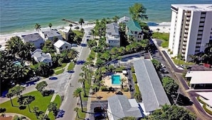An aerial view of a coastal hotel with multiple buildings, a swimming pool, and a beach in the background. - One Bed/ One Bath Condo- Step From Siesta Key Beach with Pool On Property! (Siesta Key)