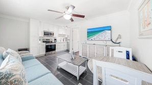 A modern living room with a sofa, a dining table, and a TV mounted on the wall. - One Bed/ One Bath Condo- Step From Siesta Key Beach with Pool On Property! (Siesta Key)