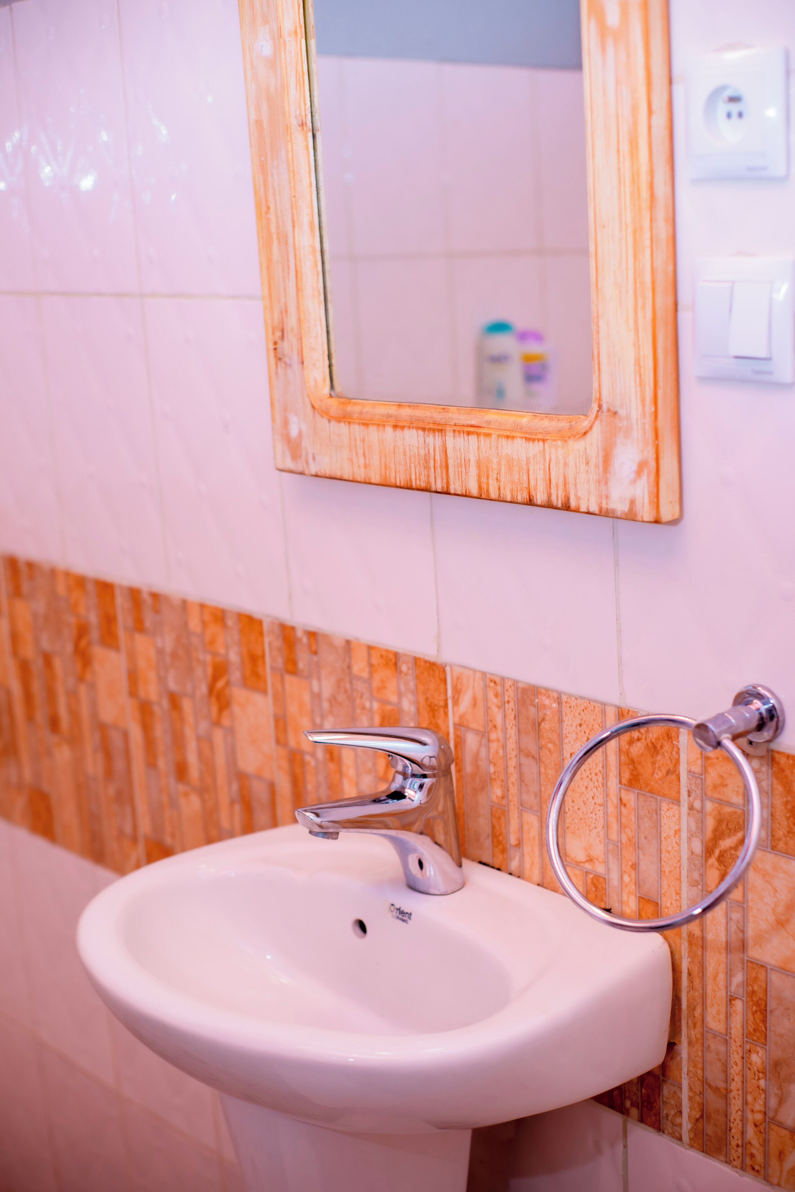 Ein Badezimmer mit einem weißen Waschbecken, einem spiegel mit Holzrahmen und einem Handtuchhalter.