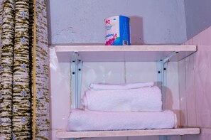 A bathroom with a shelf holding a roll of toilet paper and two folded towels. - Little birds paradise (Cyuve)