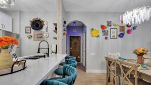 Una cocina moderna con una isla central, taburetes de bar y un comedor con sillas de madera y una mesa.