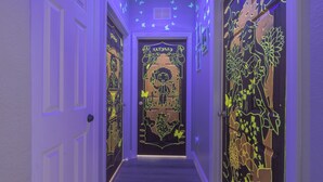 Un pasillo con puertas que exhiben obras de arte iluminadas y una puerta central con la leyenda 'ANTONIO'.