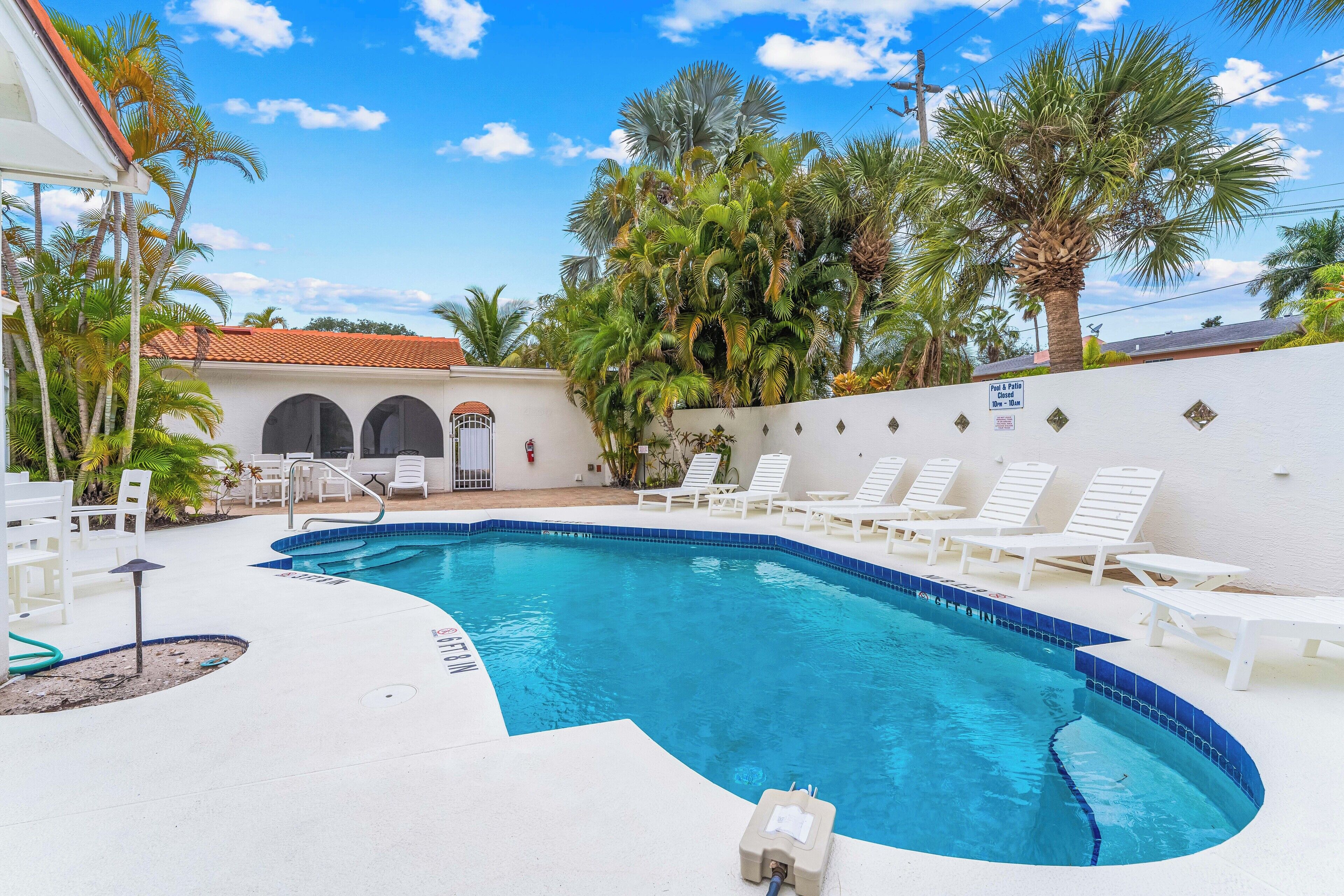 A swimming pool with white lounge chairs and palm trees.