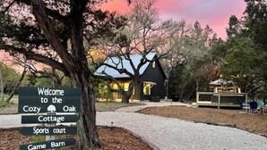 Un cartel indica el camino a una acogedora cabaña de roble, una cancha deportiva y un granero de juegos.
