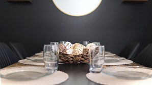 Una mesa de comedor dispuesta con platos, vasos y un centro de elementos decorativos.