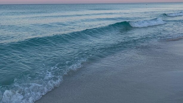 Ein Strand mit Wellen und blauem Himmel.