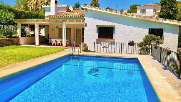 En rektangulær swimmingpool med en klar, blå vandoverflade, omgivet af en belagt terrasse.