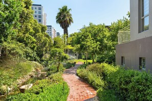 A pathway flanked by lush greenery and a building with a modern design.