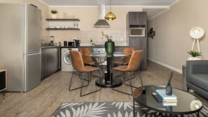 Una cocina moderna con horno empotrado, refrigerador y comedor con mesa redonda y cuatro sillas.