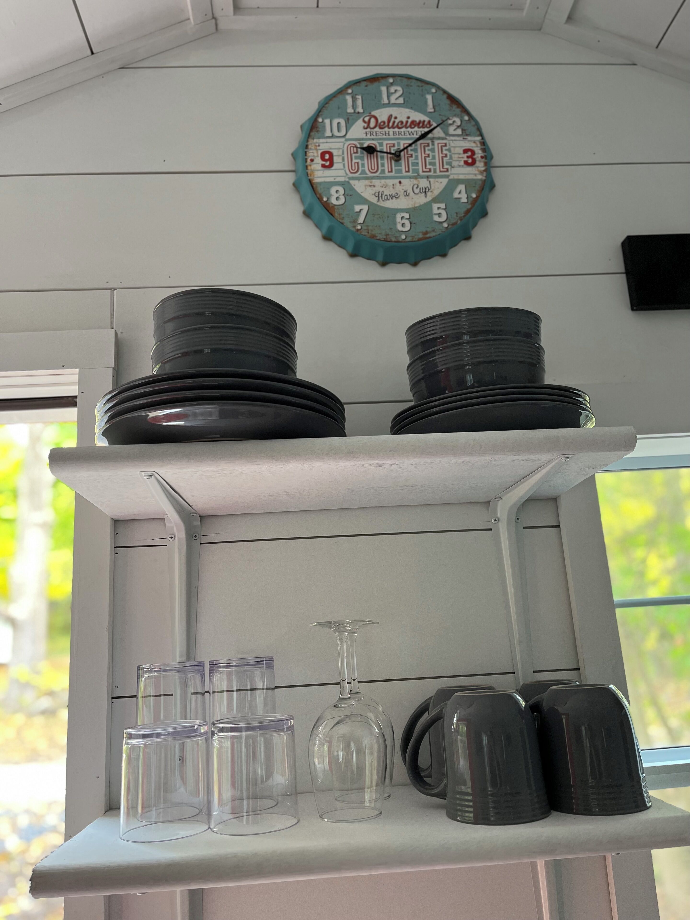 Un comptoir de cuisine avec une horloge, des assiettes, des verres et un verre à vin.