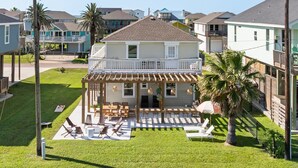A two-story house with a covered patio and outdoor seating area. - Walk to Beach, BBQ Patio Area, Community Pool, Games: Beach Soulcation (Galveston)