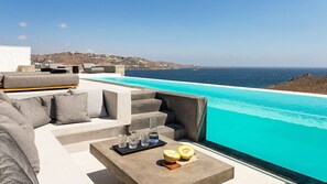 Ein moderner Sitzbereich im Freien mit Pool und Meerblick.