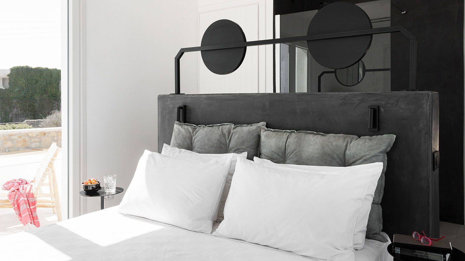 A bedroom with a large bed, a headboard with circular designs, and a view of the outdoors.