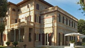 A large stone building with a central courtyard, multiple balconies, and a covered outdoor seating area.