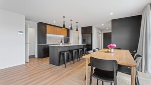 Una cocina moderna con una isla central, taburetes de bar e iluminación colgante.