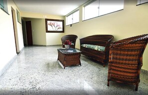 A hallway with wicker furniture, a glass coffee table, and a framed picture on the wall. - Domus Cidade Nobre (Ipatinga)