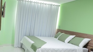 A hotel room with a bed, curtains, and a green wall. - Domus Cidade Nobre (Ipatinga)