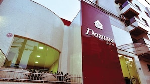 A hotel entrance with a large maroon sign reading "Domus HOTEL". - Domus Cidade Nobre (Ipatinga)