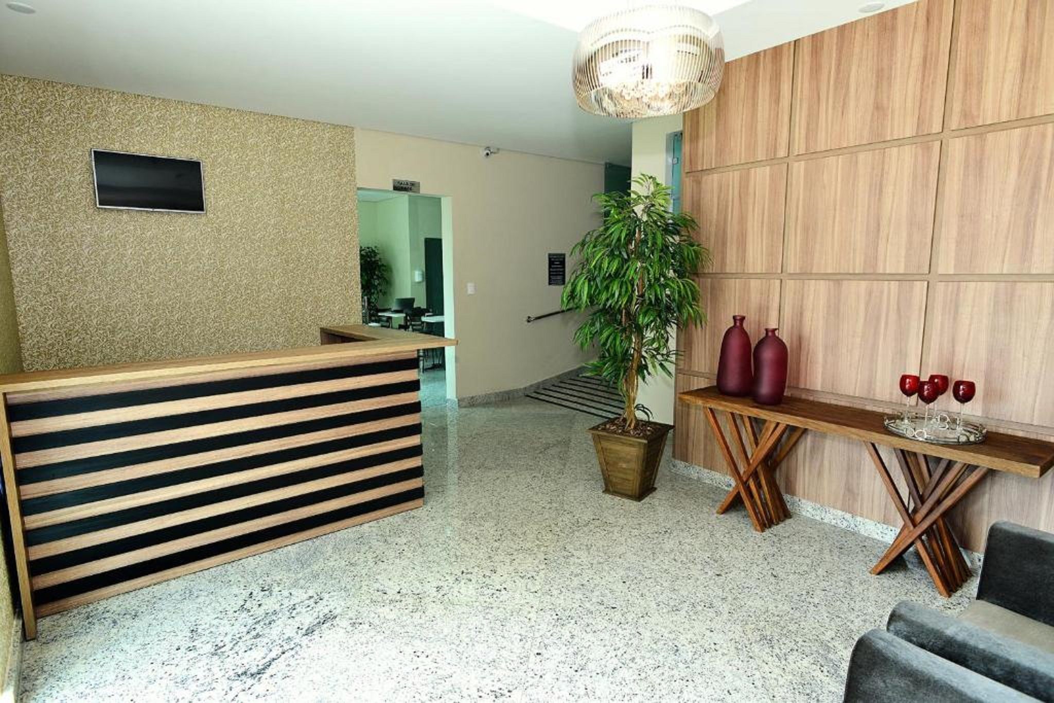 A reception area with a wooden reception desk, a potted plant, and a wall-mounted television.