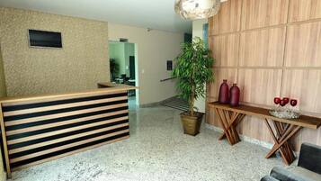 A reception area with a wooden reception desk, a potted plant, and a wall-mounted television.