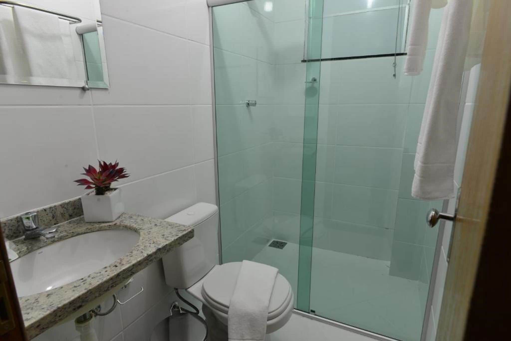 Ein Badezimmer mit einer Duschkabine, einem Waschbecken mit einer Granit-Arbeitsplatte und einer Toilette.