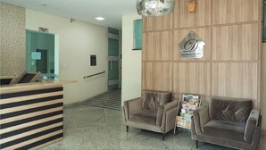 A hotel reception area with a reception desk, two sofas, a chandelier, and a sign for the Domus Hotel. - Domus Cidade Nobre (Ipatinga)